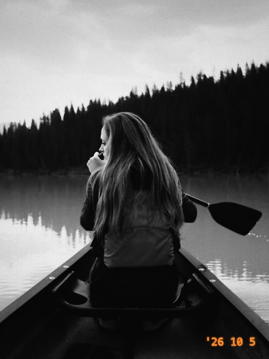 A friend paddling a canoe on a still lake, in Mono