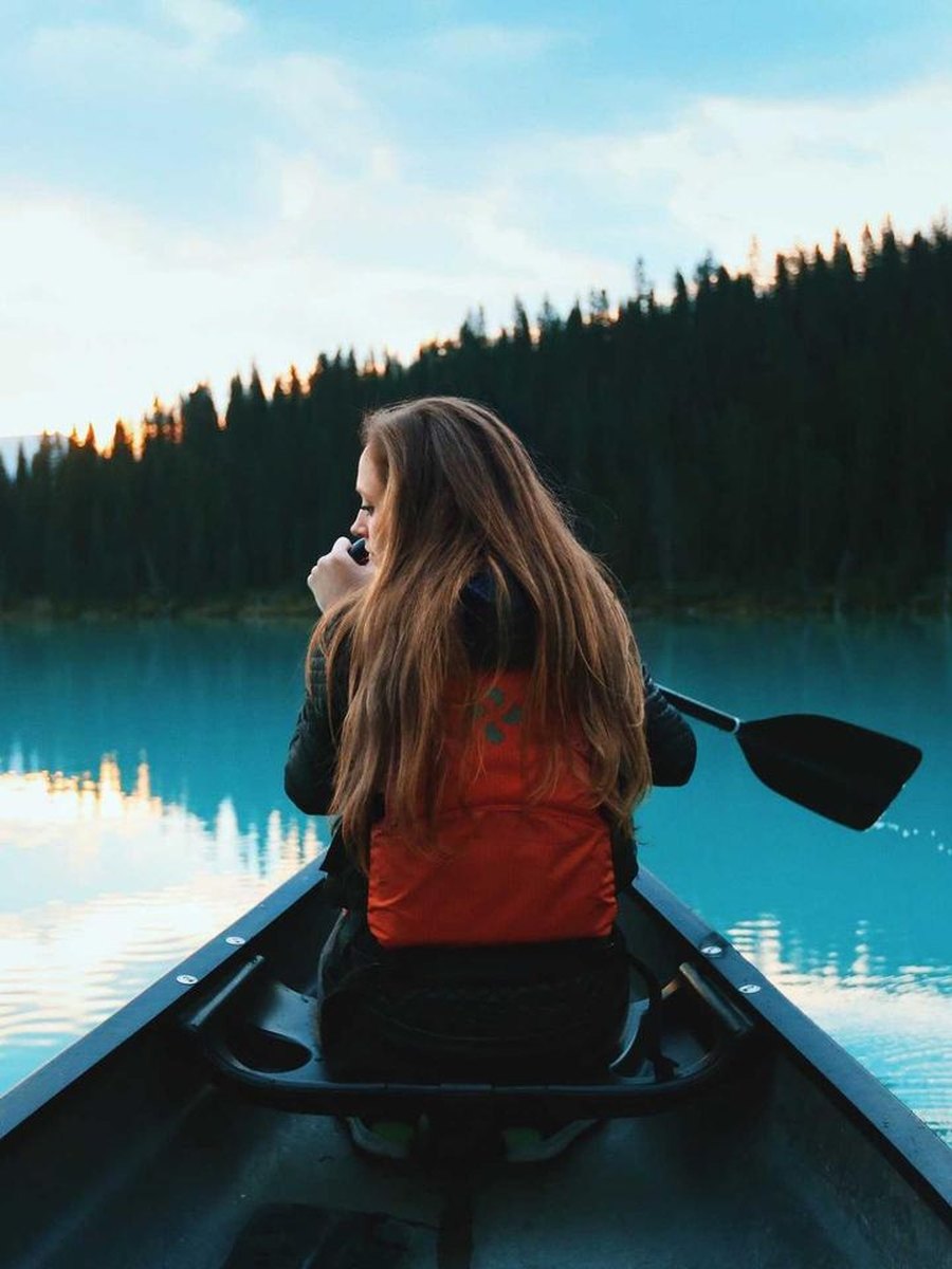 A friend paddling a canoe on a still lake, in Original