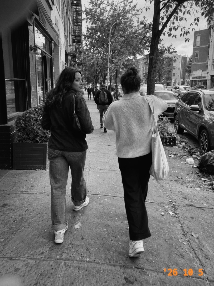 Two friends walking down a city sidewalk, in Mono