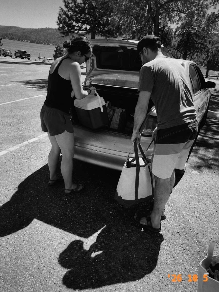 Two friends unloading a car by a lake, in Mono