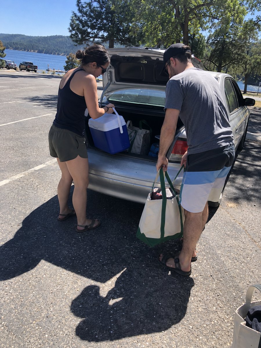 Two friends unloading a car by a lake, in Original